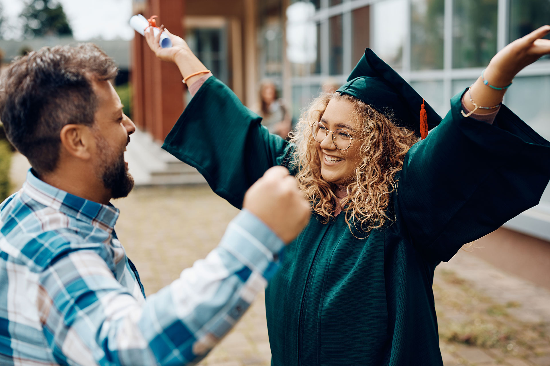 Female high school graduate celebrating with father.