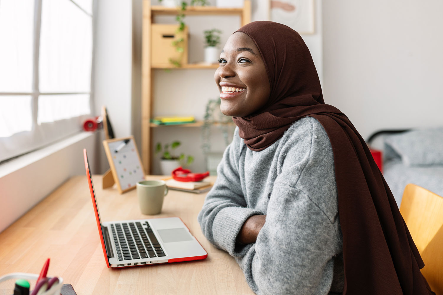 Student smiling while studying at home with a laptop during a hybrid learning day.