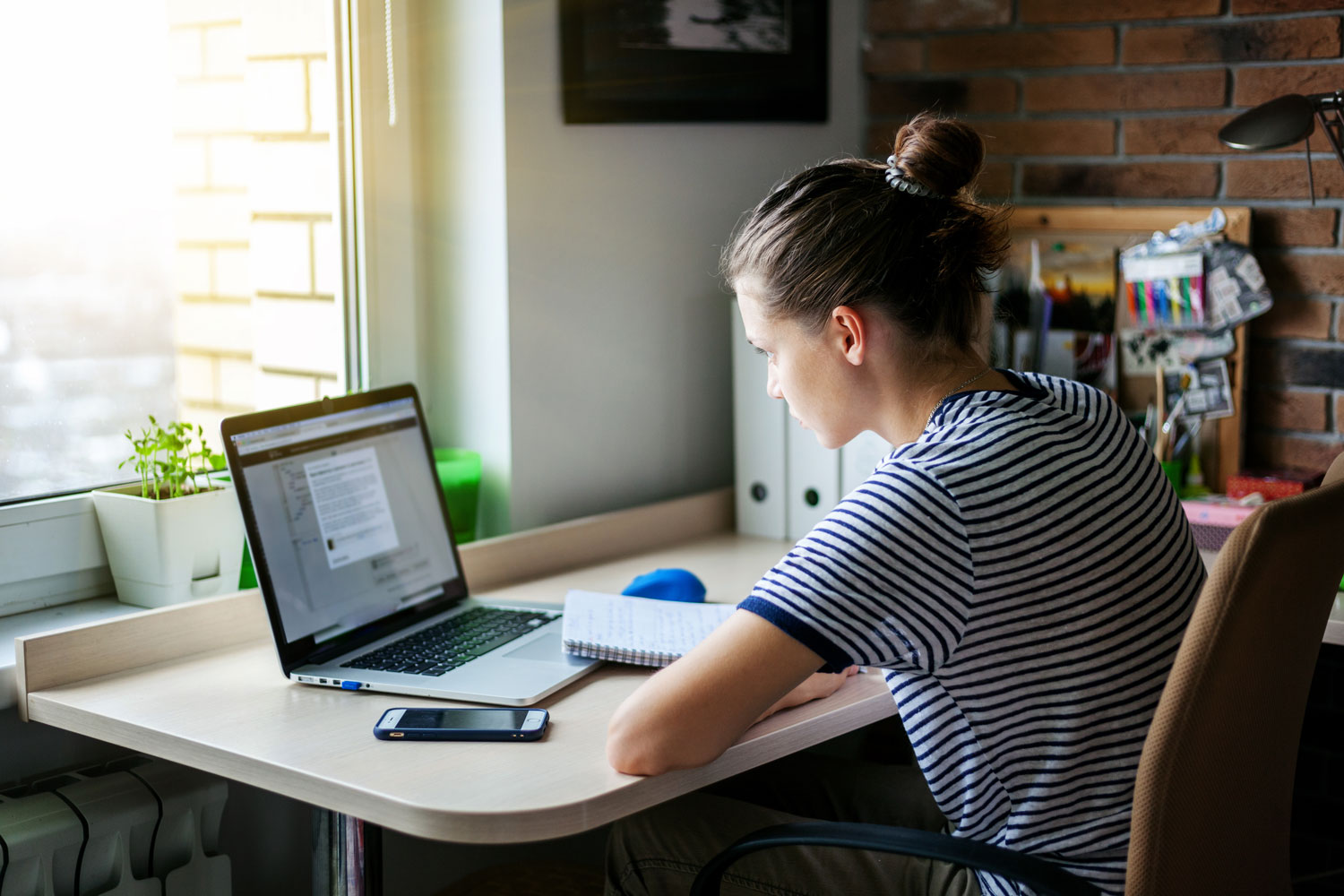 Transferring Mid-Year to an Online or Hybrid School in Minnesota Girl student working with laptop at home by the window.